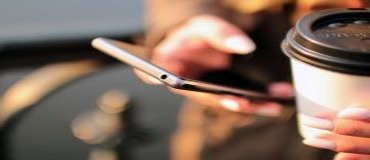 Woman's hands with mobile phone and coffee cup